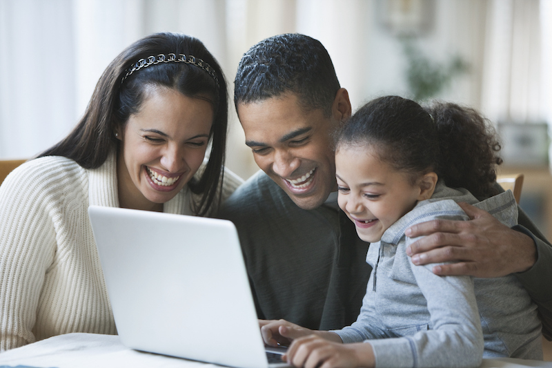 A family surrounding a laptop